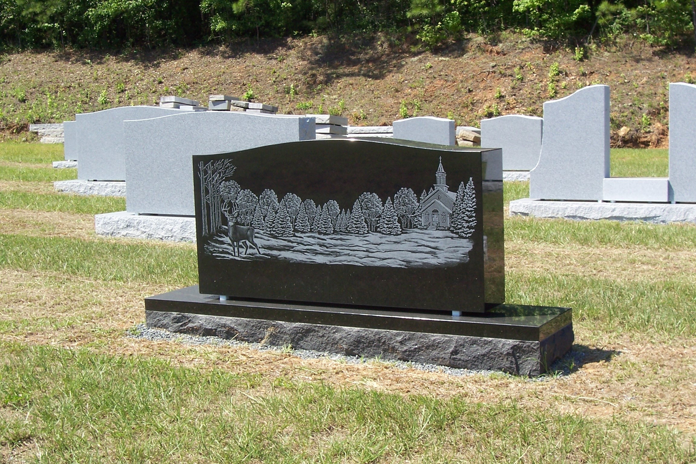 black upright monument with forest scene engraving