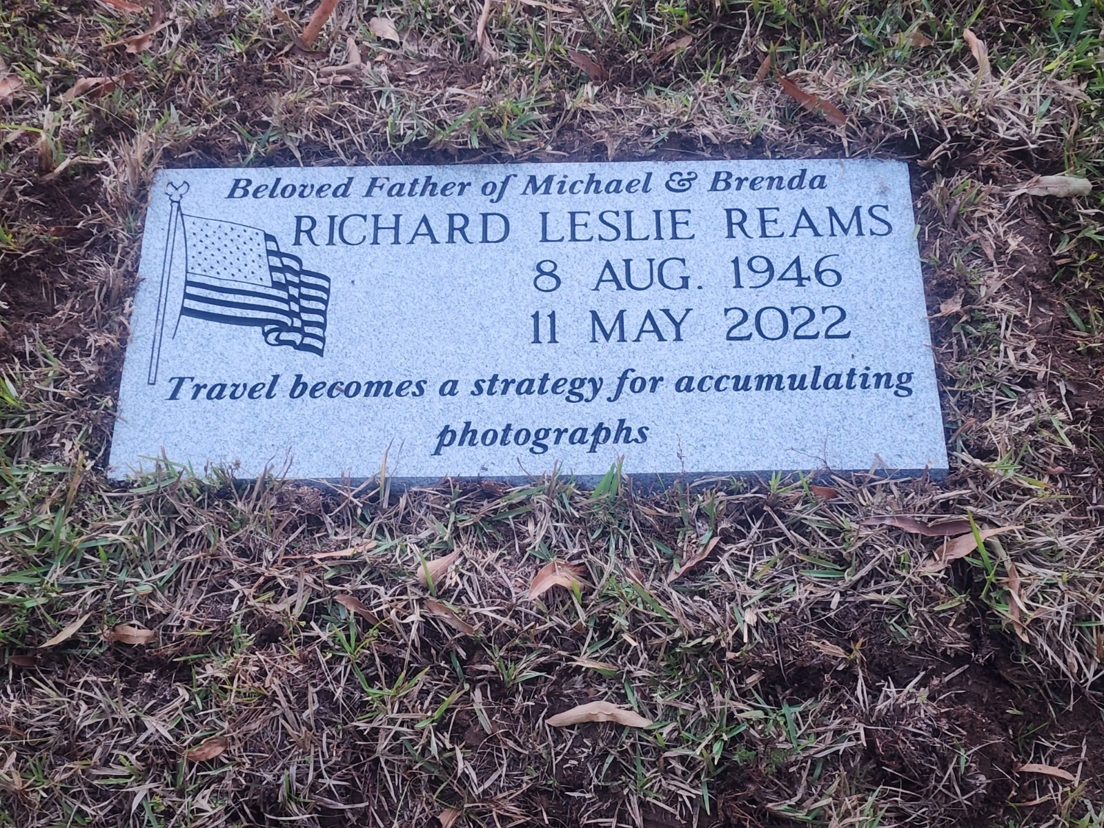 flat grey grave marker with american flag engraving